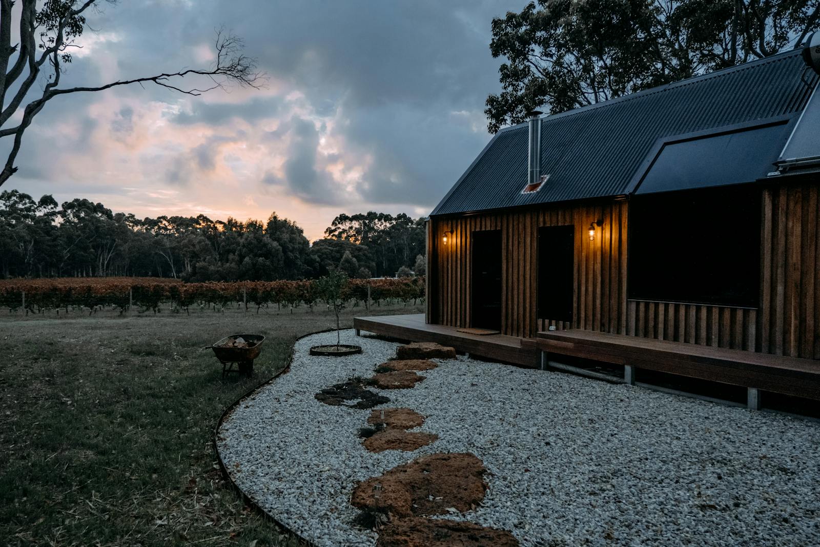 Russian River cabin with exterior lighting and gravel driveway at twilight